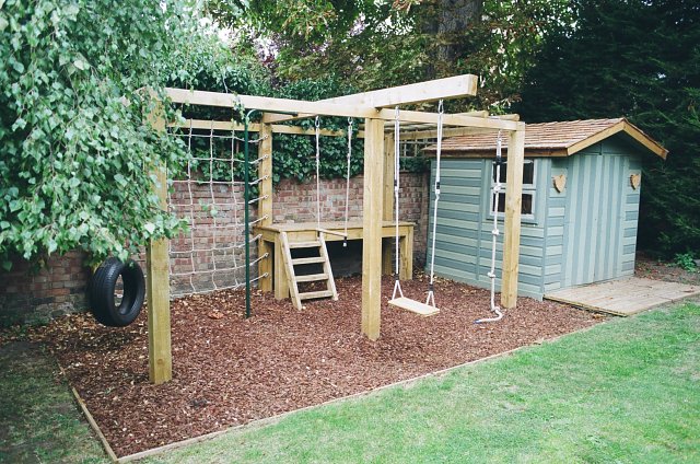 Children's playframe with swing, monkey bars, climbing net and play bark